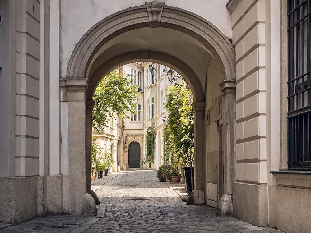 Archway leading into an inner courtyard with cobbled stones and historic house facades