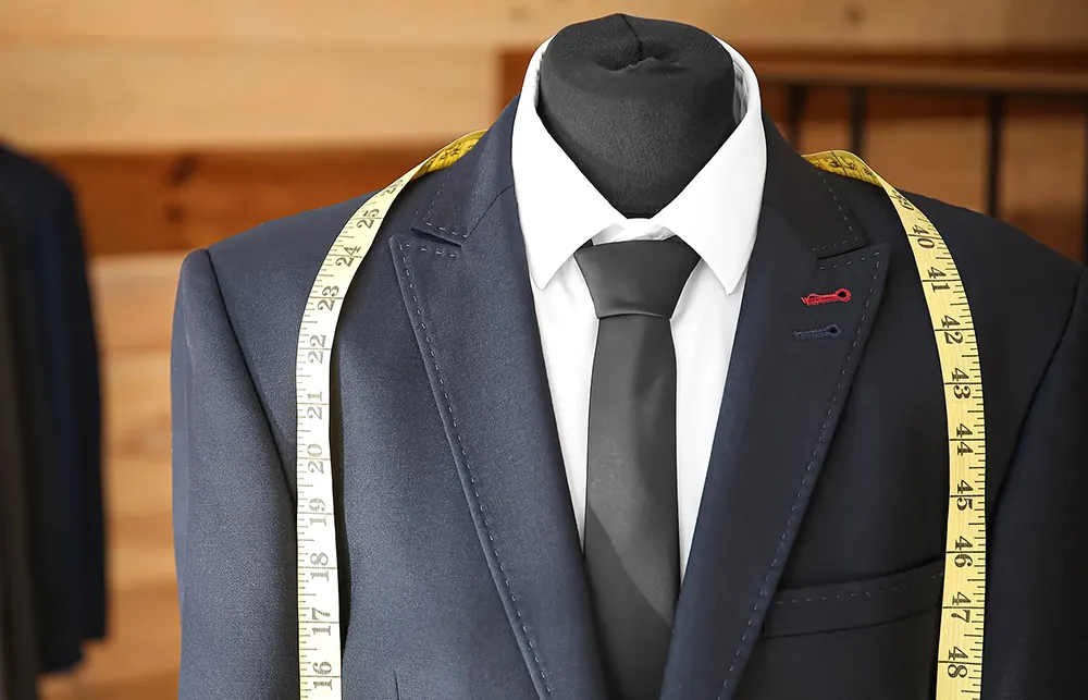A bespoke outfit on a mannequin with a tape measure around its neck, showing a client-centric approach.