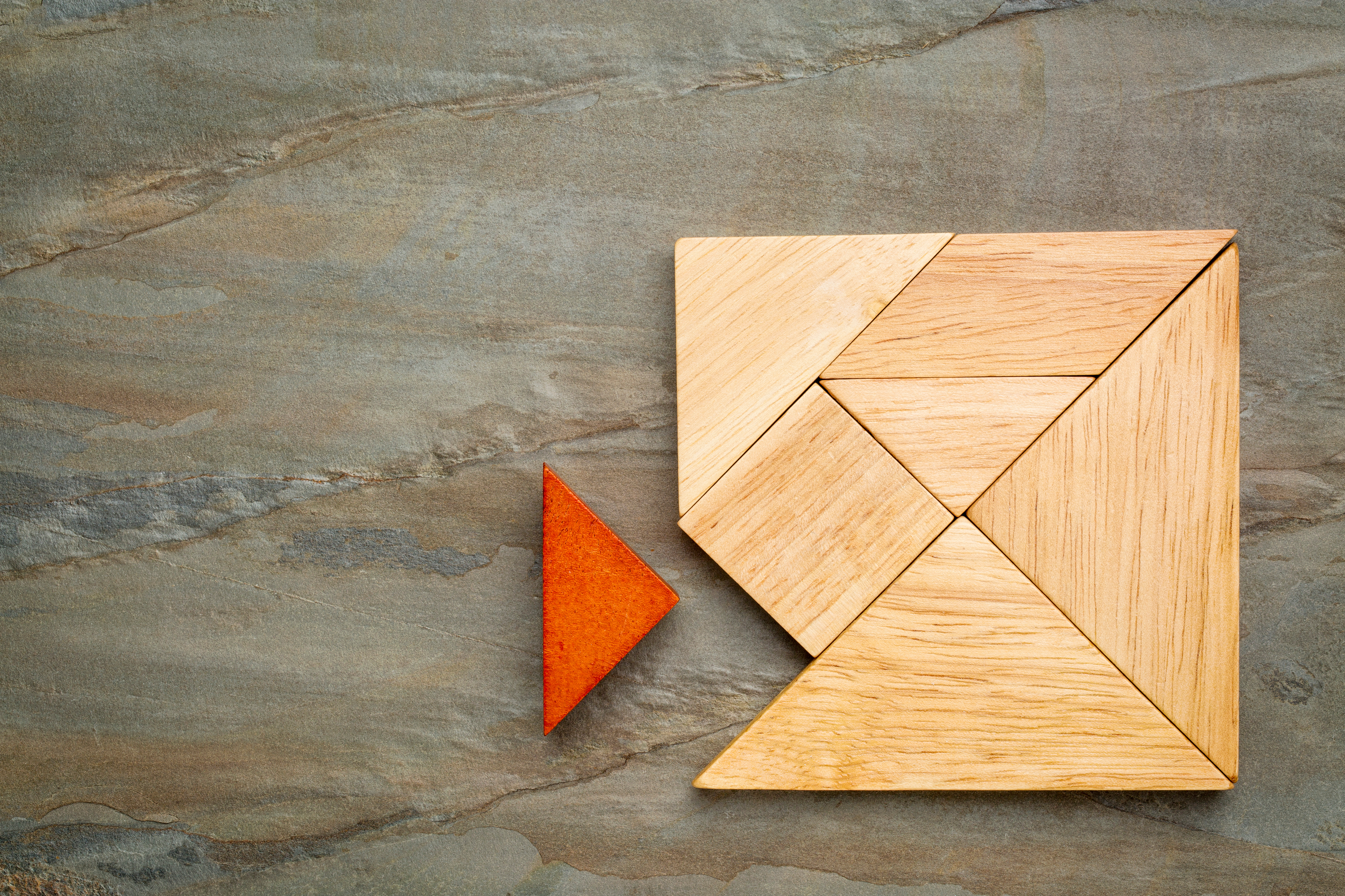 Wooden puzzle with a piece being added.