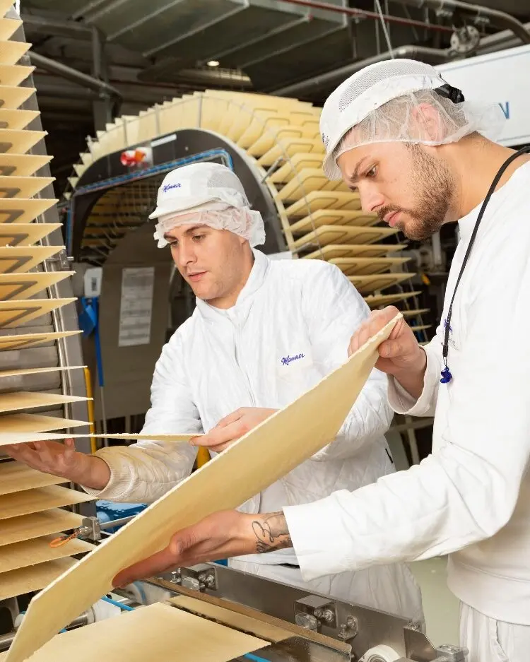 Image Credit: Manner Two Manner production workers handling fresh wafer sheets during the manufacturing process.