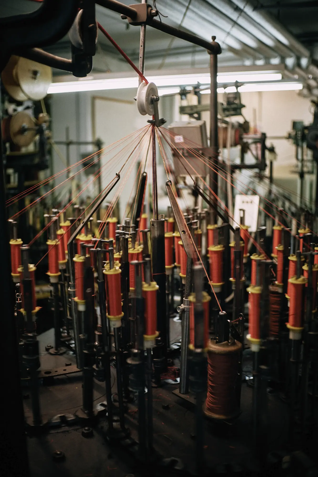 Close-up of a braiding machine with wooden bobbins arranged in a circle