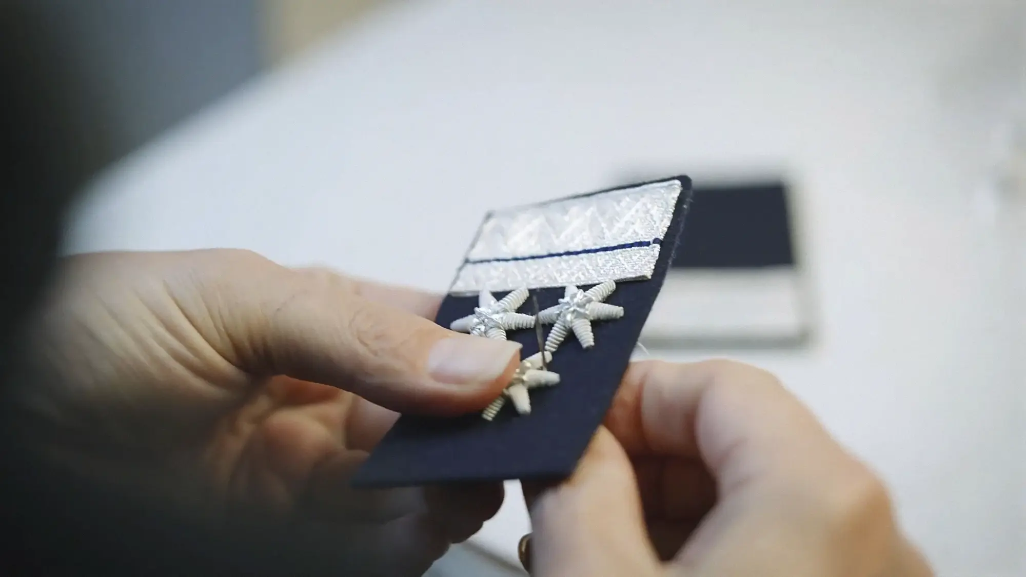 Female fingers stitching stars in a military epaulette